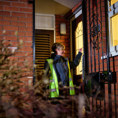 Care Link Visiting Officer knocking at a customer's door at night.