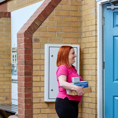 Care Link Visiting Officer holding equipment speaking to a customer at their front door